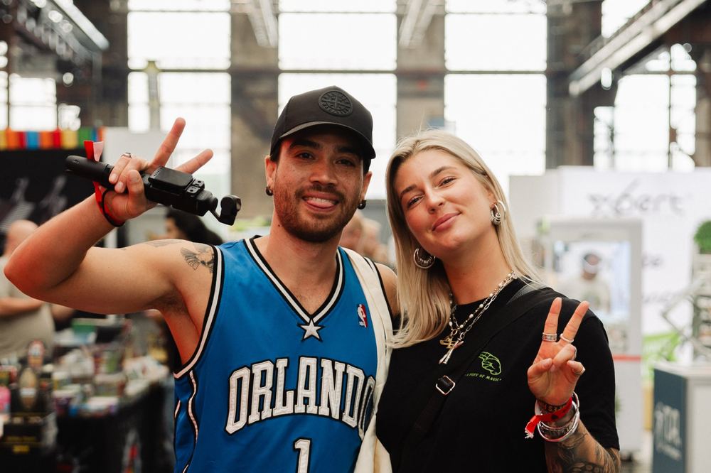 Zwei gut gelaunte Besucher mit Peace-Zeichen in der Messehalle