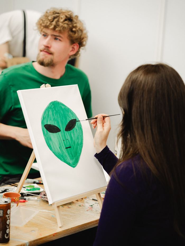 Besucherin malt ein grünes Alien auf Leinwand beim Mal-Workshop
