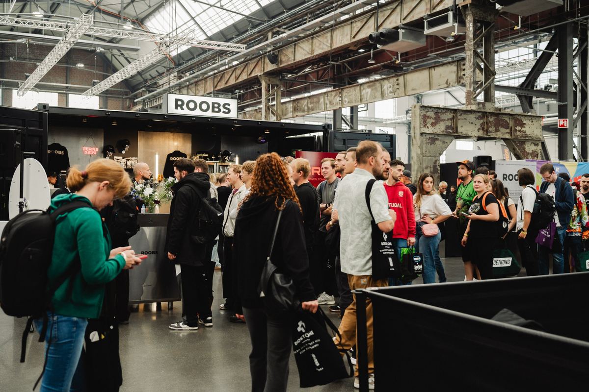 Besucher vor dem Stand von Roobs unter den Stahlträgern der Halle