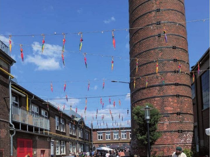 B2B-Bereich am Schornstein mit Liegestühlen, Holzstehtischen und bunten Wimpelketten